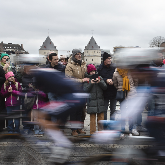 Kuurne Brussel Kuurne 2024 - Riders at the start of the race speed past fans in Kortrijk with the Broeltorens in the background