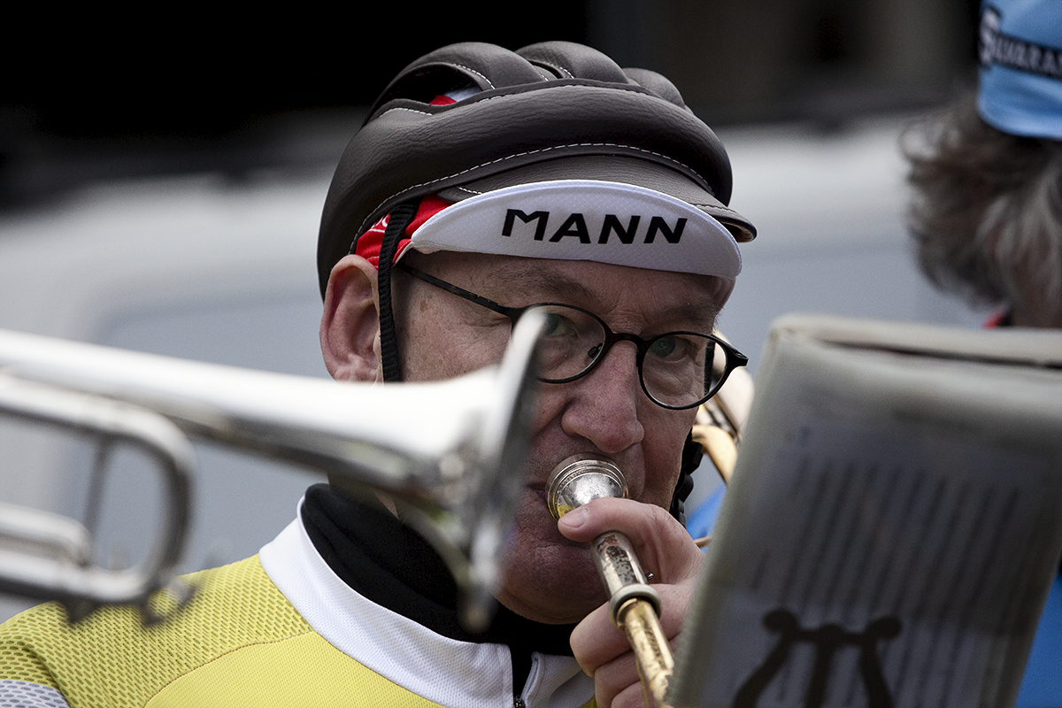 Kuurne Brussel Kuurne 2024 - A Member of a brass band dressed in old fashioned cycling gear plays the trumpet