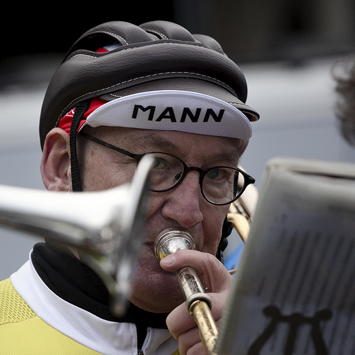 Kuurne Brussel Kuurne 2024 - A Member of a brass band dressed in old fashioned cycling gear plays the trumpet