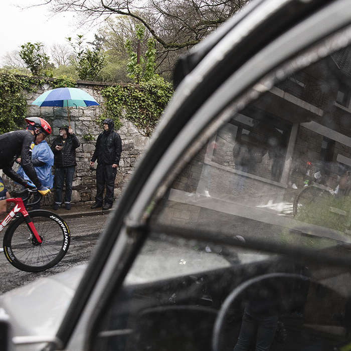 La Flèche Wallonne 2024 - A rider seen through the window of a 2CV on the Mur de Huy