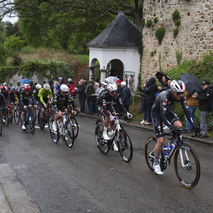 La Flèche Wallonne 2025 - A group of riders make their way past one of the small white chapels on Mur de Huy