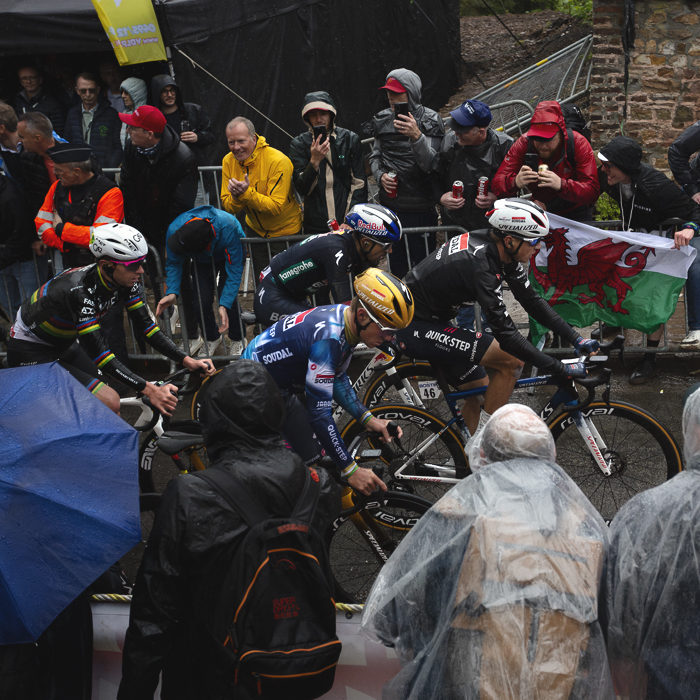 La Flèche Wallonne 2025 - The peloton passes supporters waving a Welsh flag on the Mur de Huy