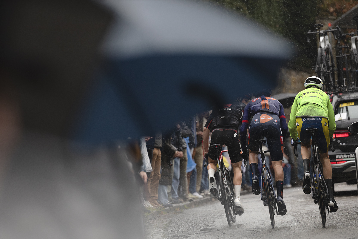 La Flèche Wallonne 2025 - Riders are framed by a spectator's umbrella on the Mur de Huy
