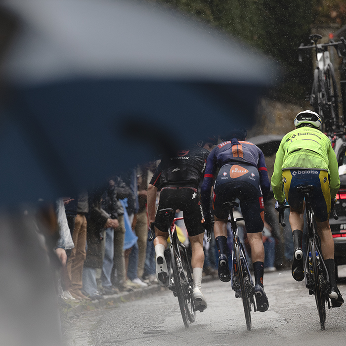 La Flèche Wallonne 2025 - Riders are framed by a spectator's umbrella on the Mur de Huy