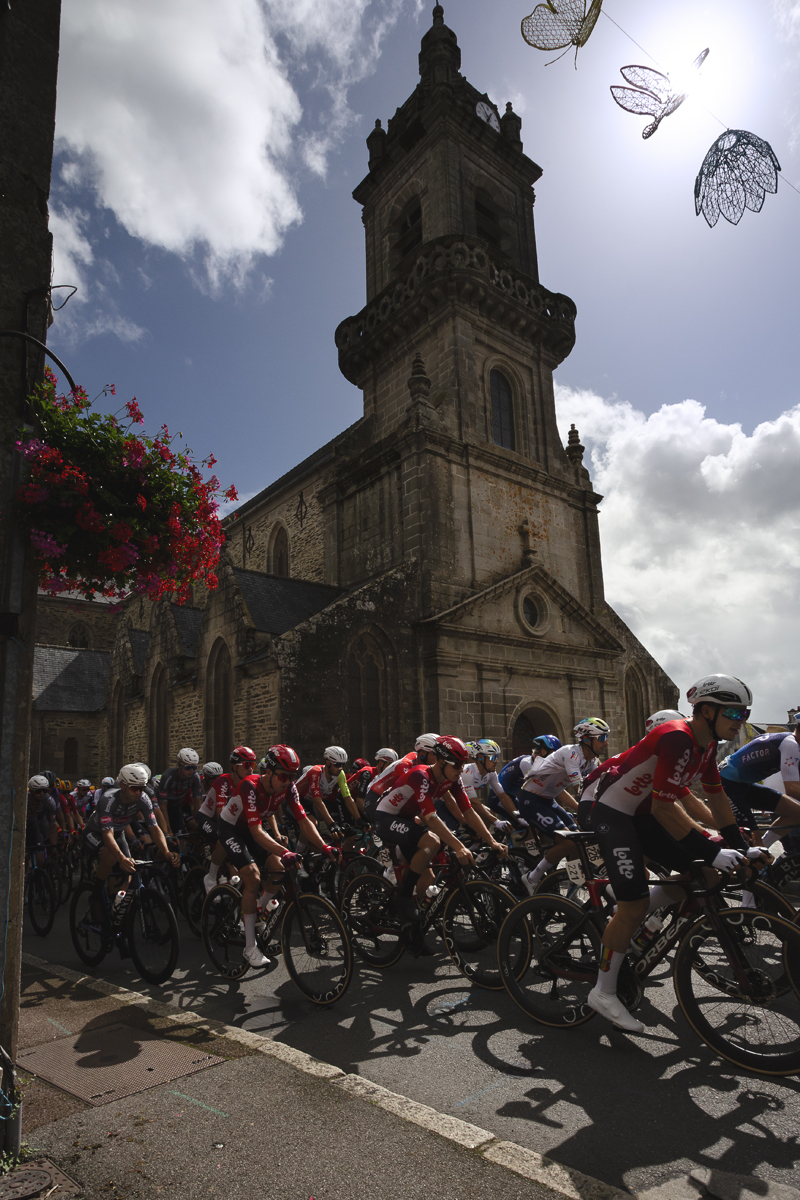 Bretagne Classic - Ouest-France 2025 - The peloton passes in front of the church in Châteauneuf-du-Faou