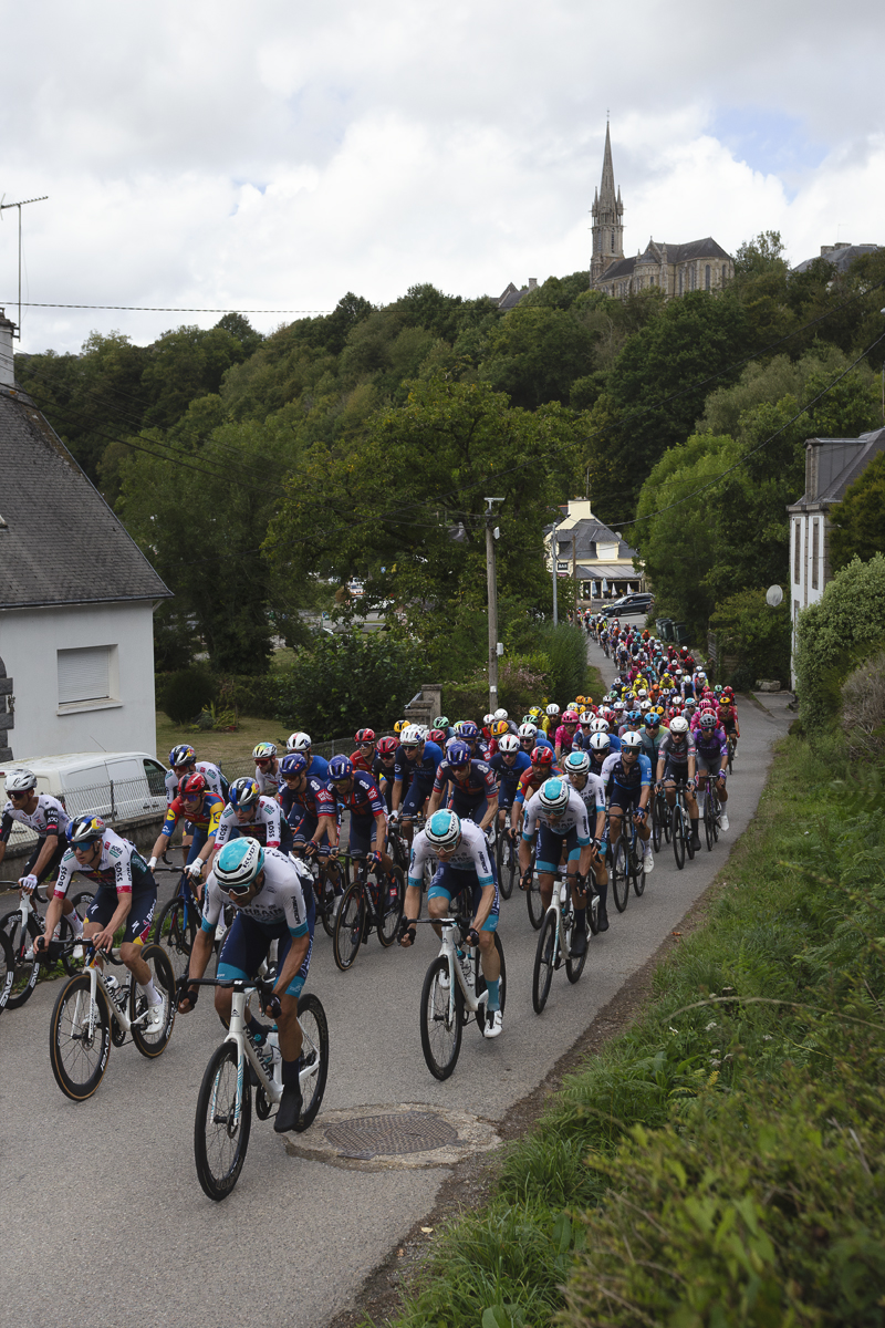 Bretagne Classic - Ouest-France 2025 - The peloton seen stretching out into the distance in Châteauneuf-du-Faou