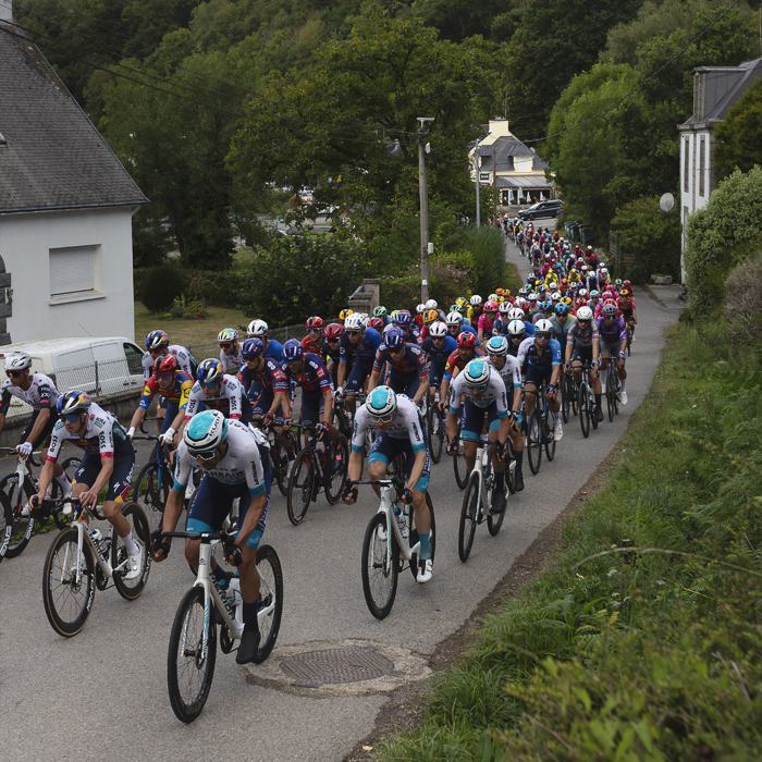 Bretagne Classic - Ouest-France 2025 - The peloton seen stretching out into the distance in Châteauneuf-du-Faou