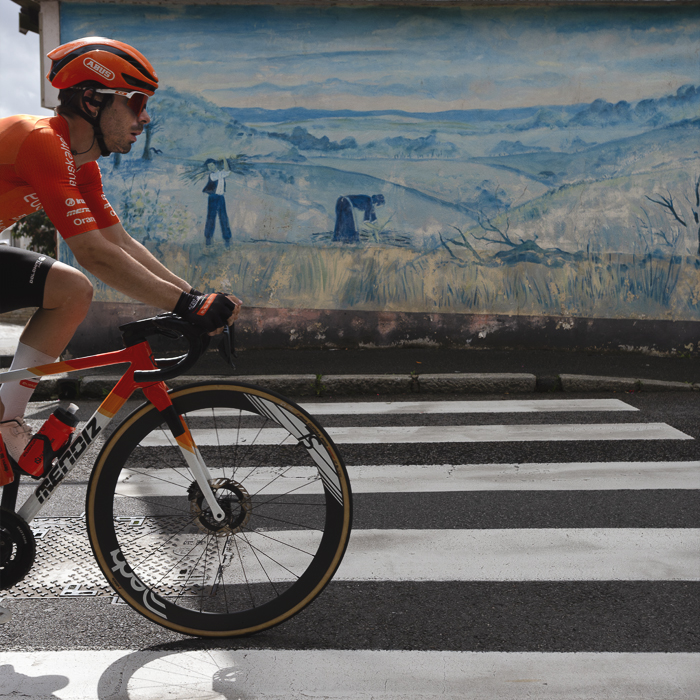 Bretagne Classic - Ouest-France 2025 - Iker Mintegi cycles over a zebra crossing in front of a mural depicting a rural scene