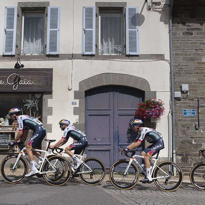 Bretagne Classic - Ouest-France 2025 - The Red Bull - BORA - hansgrohe pass in front of a large arched door in Châteauneuf-du-Faou