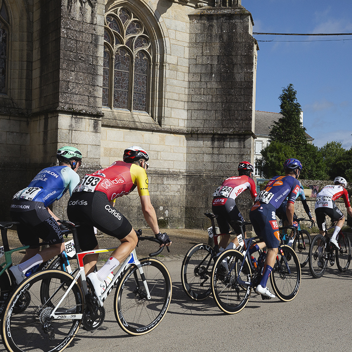 Bretagne Classic - Ouest-France 2025 - The peloton passes in front of the church in Kernascléden