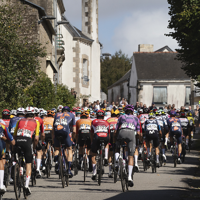 Bretagne Classic - Ouest-France 2025 - A rear view of the peloton as it passes up a street framed by traditional houses