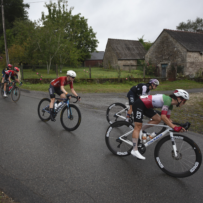 Classic Lorient Agglomération - Ceratizit 2025 - Riders pass in front of stone farm buildings at Le Temple