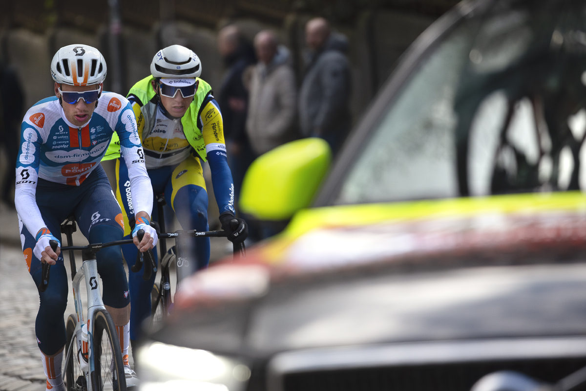 Liège-Bastogne-Liège 2024 - Martijn Tusveld & Lars Craps framed by a race vehicle