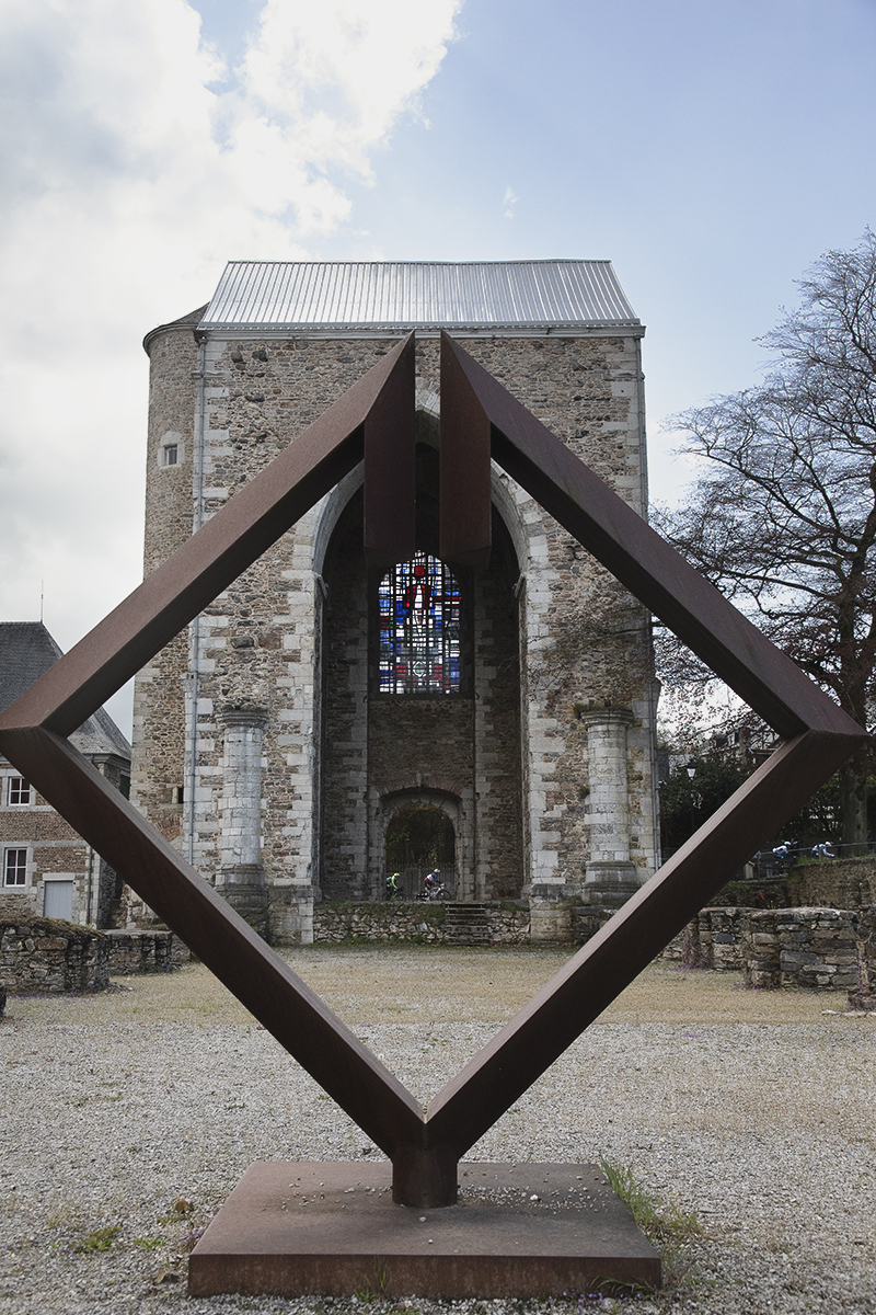 Liège-Bastogne-Liège 2024 - Riders framed through the Toren Abdijkerk in Stavelot