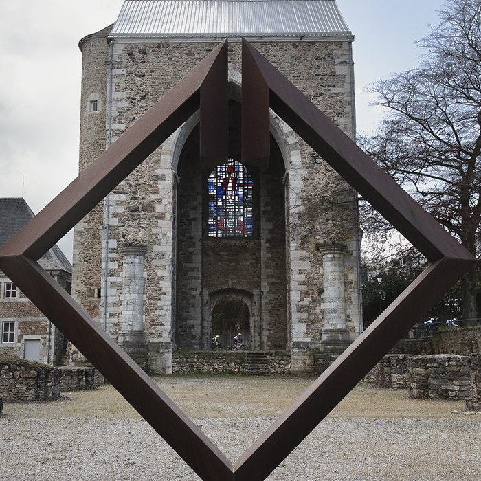 Liège-Bastogne-Liège 2024 - Riders framed through the Toren Abdijkerk in Stavelot