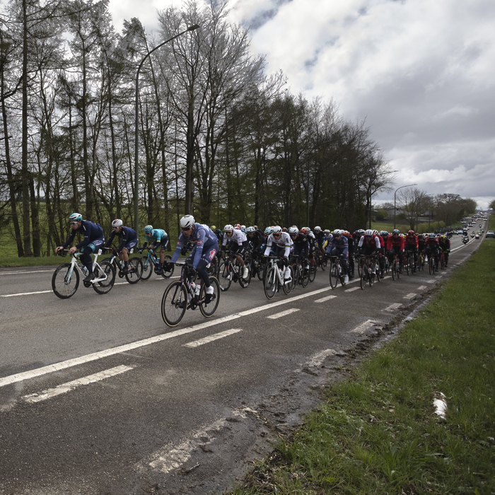 Liège-Bastogne-Liège 2024 - A group of riders pass by trees at Vaux