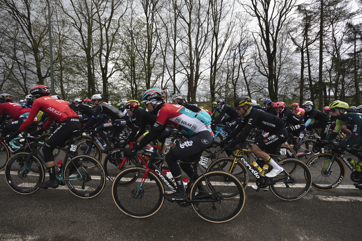 Liège-Bastogne-Liège 2024 - A side view of riders passing in front of trees at Vaux