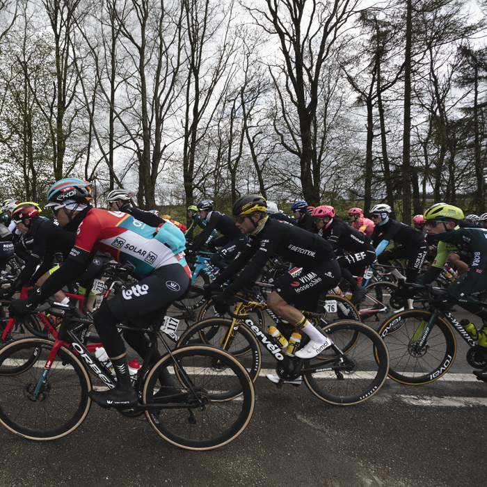 Liège-Bastogne-Liège 2024 - A side view of riders passing in front of trees at Vaux