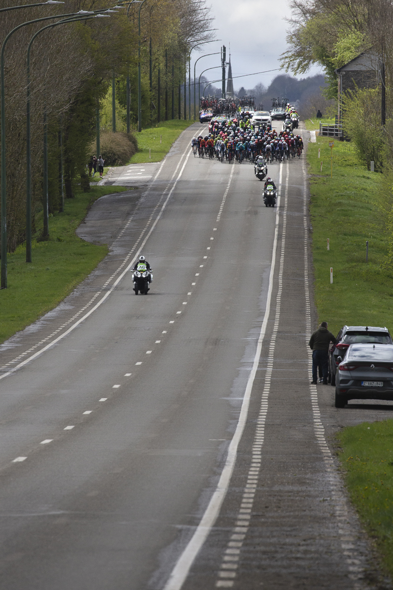 Liège-Bastogne-Liège 2024 - The peloton approaches down a long straight road at Vaux