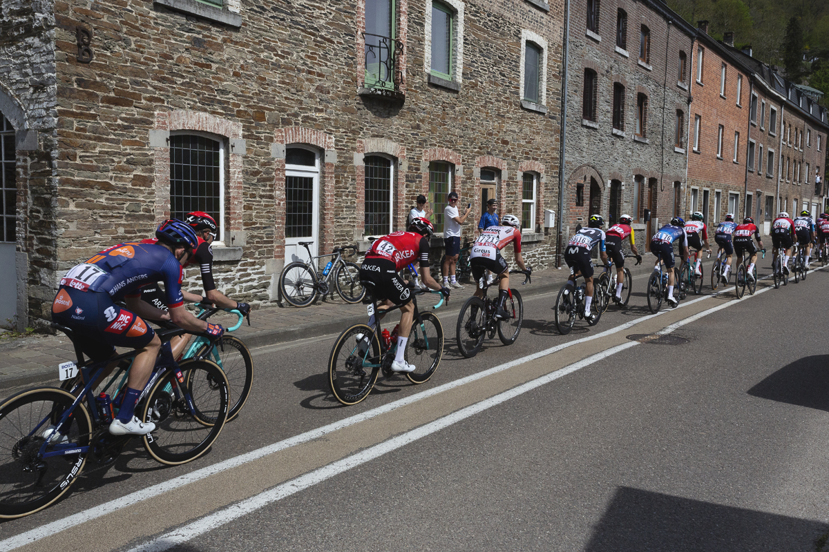 Liege Bastogne Liege 2025 - Riders pass tall stone houses at La Roché-en-Ardenne