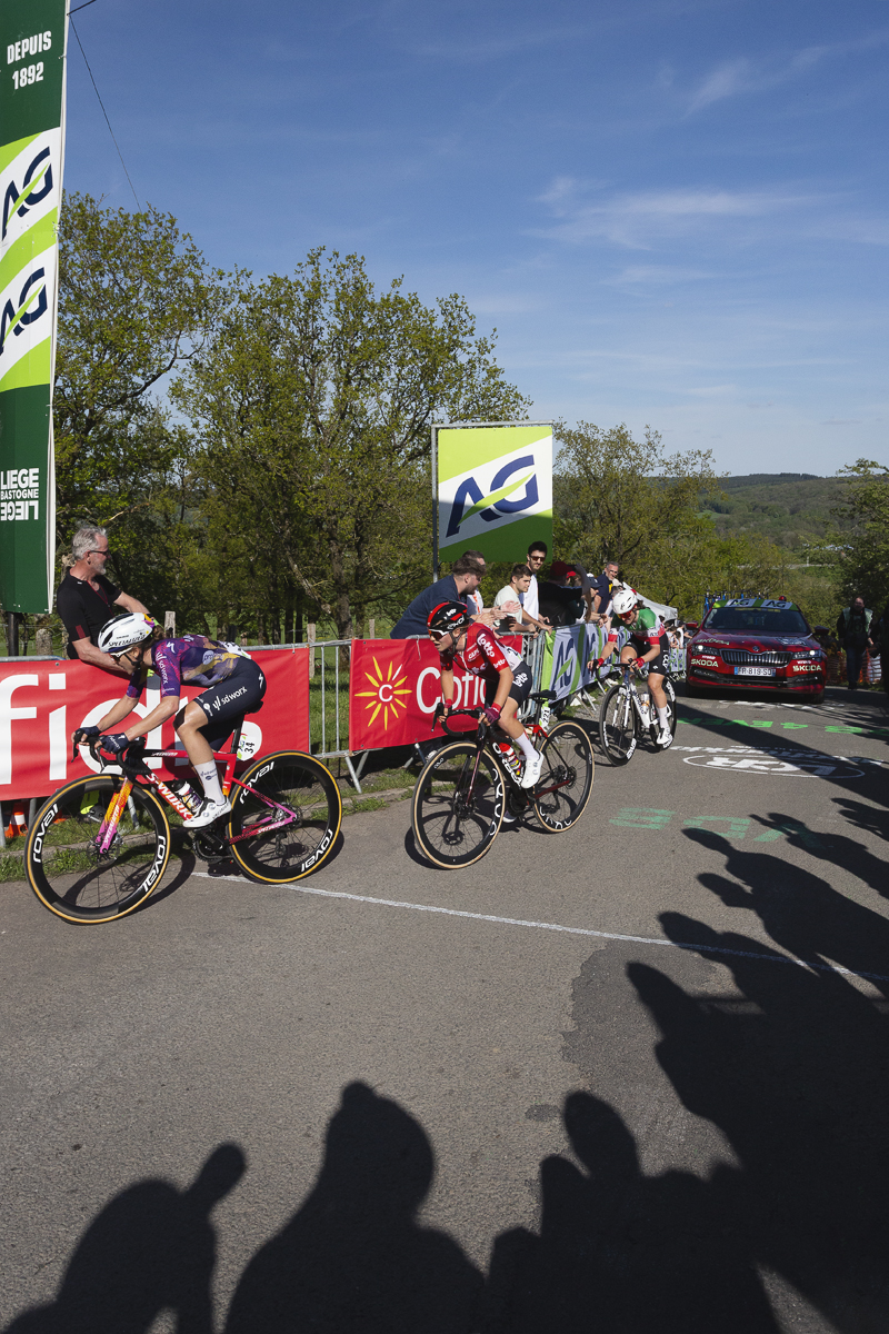 Liège Bastogne Liège Femmes 2025 - The shadows of fans are cast on the road as riders finish the climb