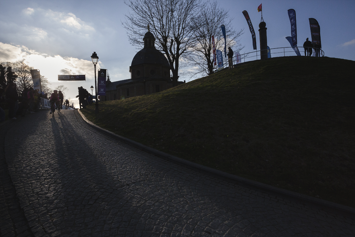 Omloop Nieuwsblad Vrouwen 2025 - Riders crest the Muur van Geraardsbergen silhouetted in the winter sun