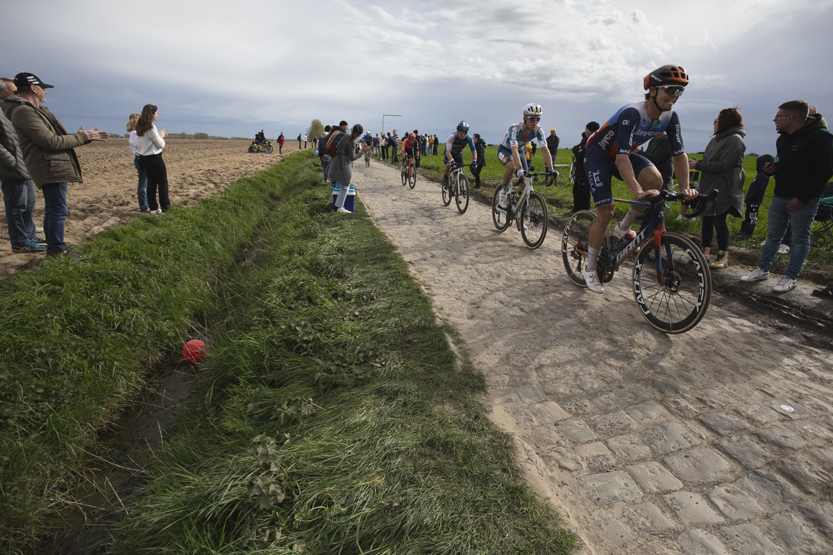 Paris Roubaix 2024 - A red balloon at the side of the race with fans watching on at Camphin-en-Pévèle