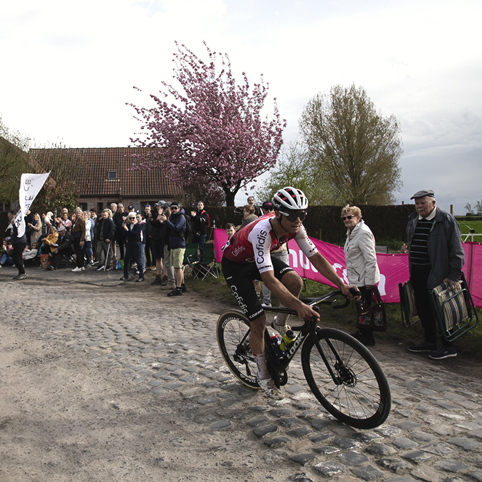 Paris Roubaix 2024 - Milan Fretin of Cofidis rounds a corner past a blossom laden tree on Carrefour de l’Arbre
