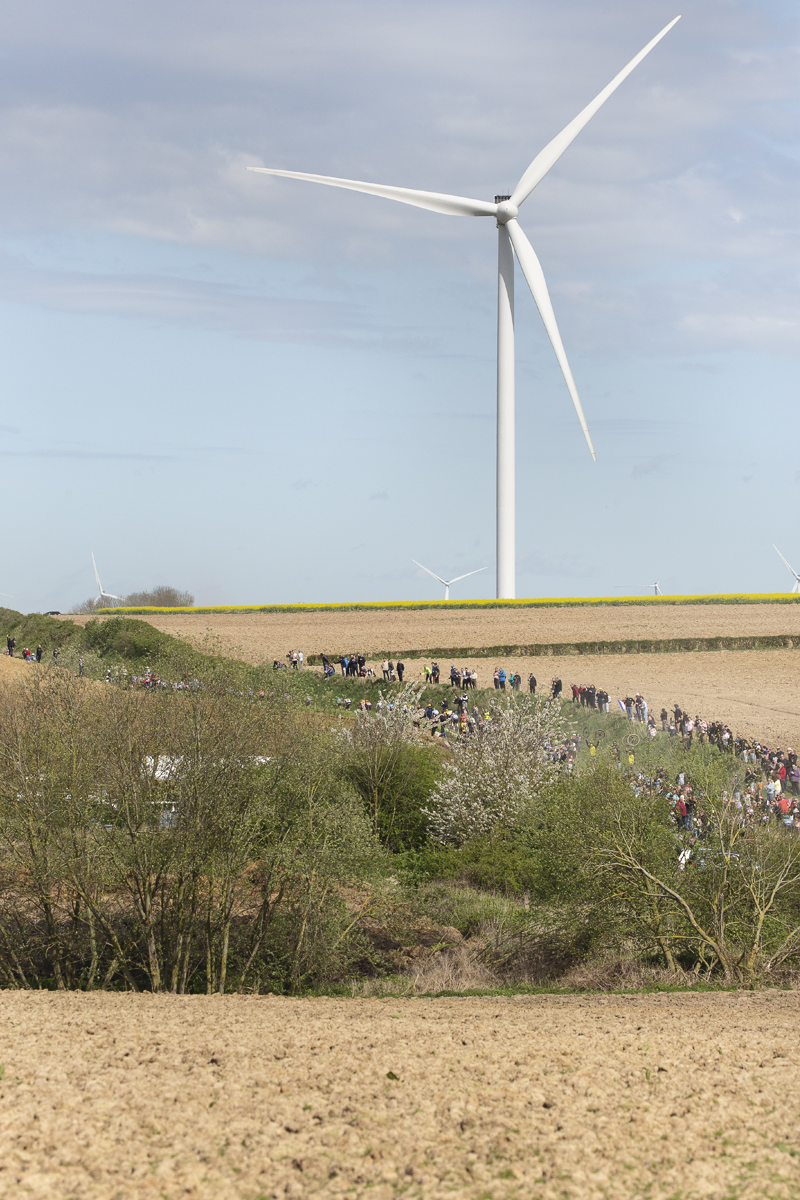 Paris Roubaix 2024 - A wind turbine on Quiévy à Saint-Python with the peloton coming into view
