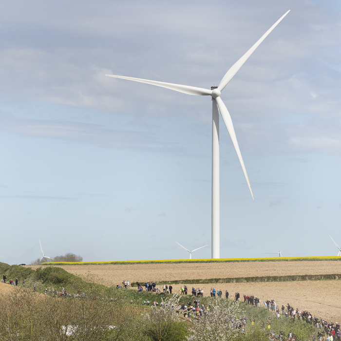 Paris Roubaix 2024 - A wind turbine on Quiévy à Saint-Python with the peloton coming into view