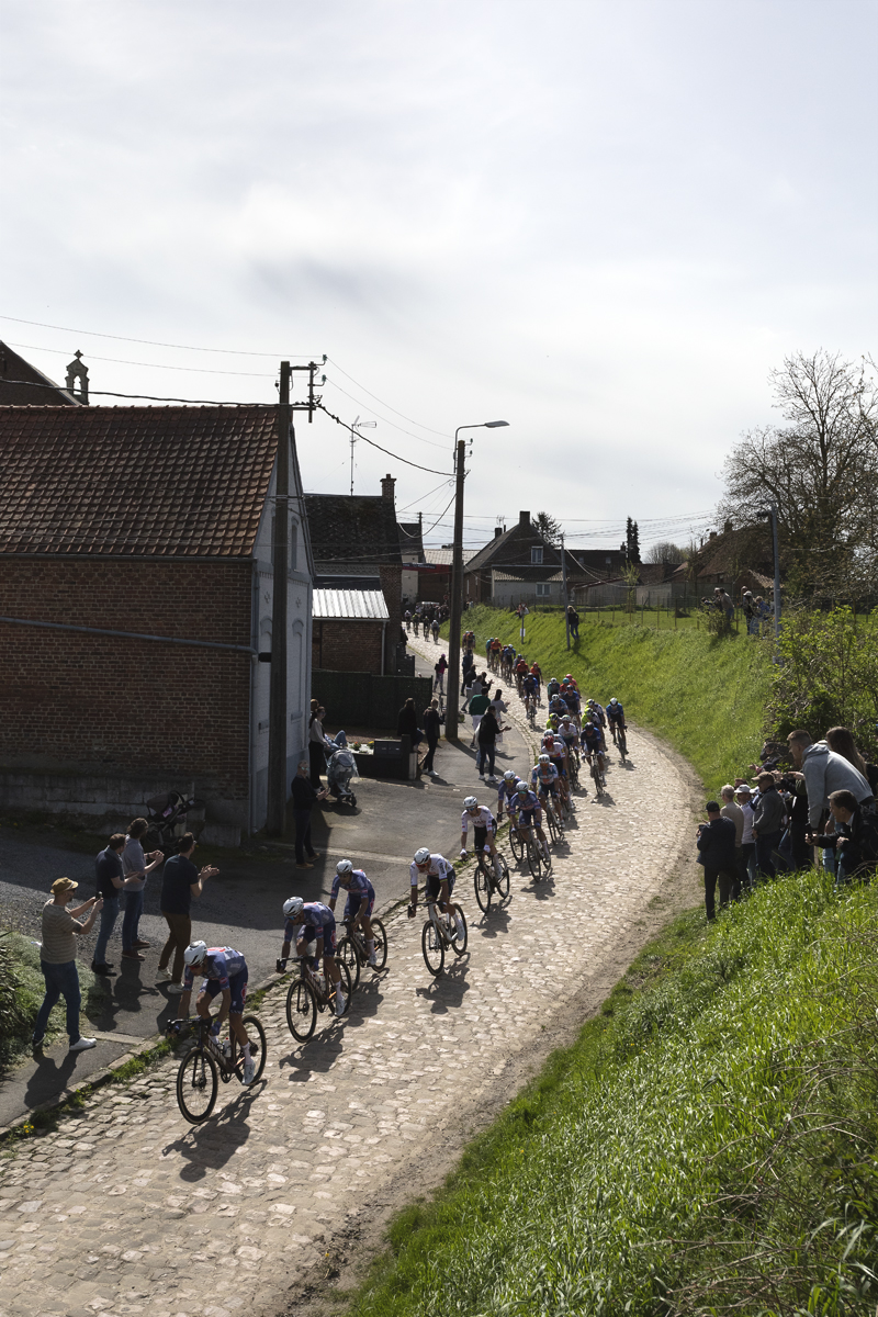 Paris Roubaix 2024 - A strung out group of riders enters the Quiévy à Saint-Python sector