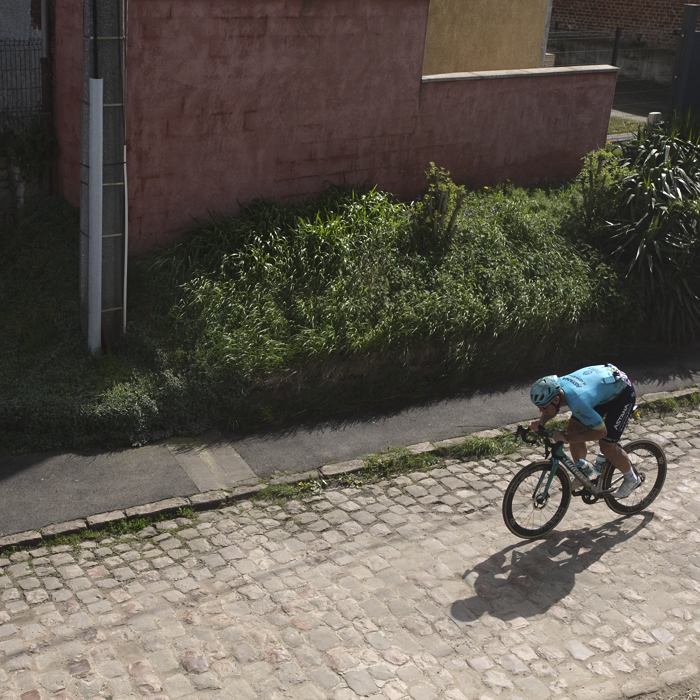 Paris Roubaix 2024 - Gleb Syritsa of Astana Qazaqstan Team seen from above passes a young girl at the start of the Quiévy à Saint-Python sector