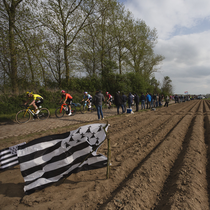 Paris Roubaix 2025 - A flag of Brittany planted in the furrows of a ploughed field as the riders pass by