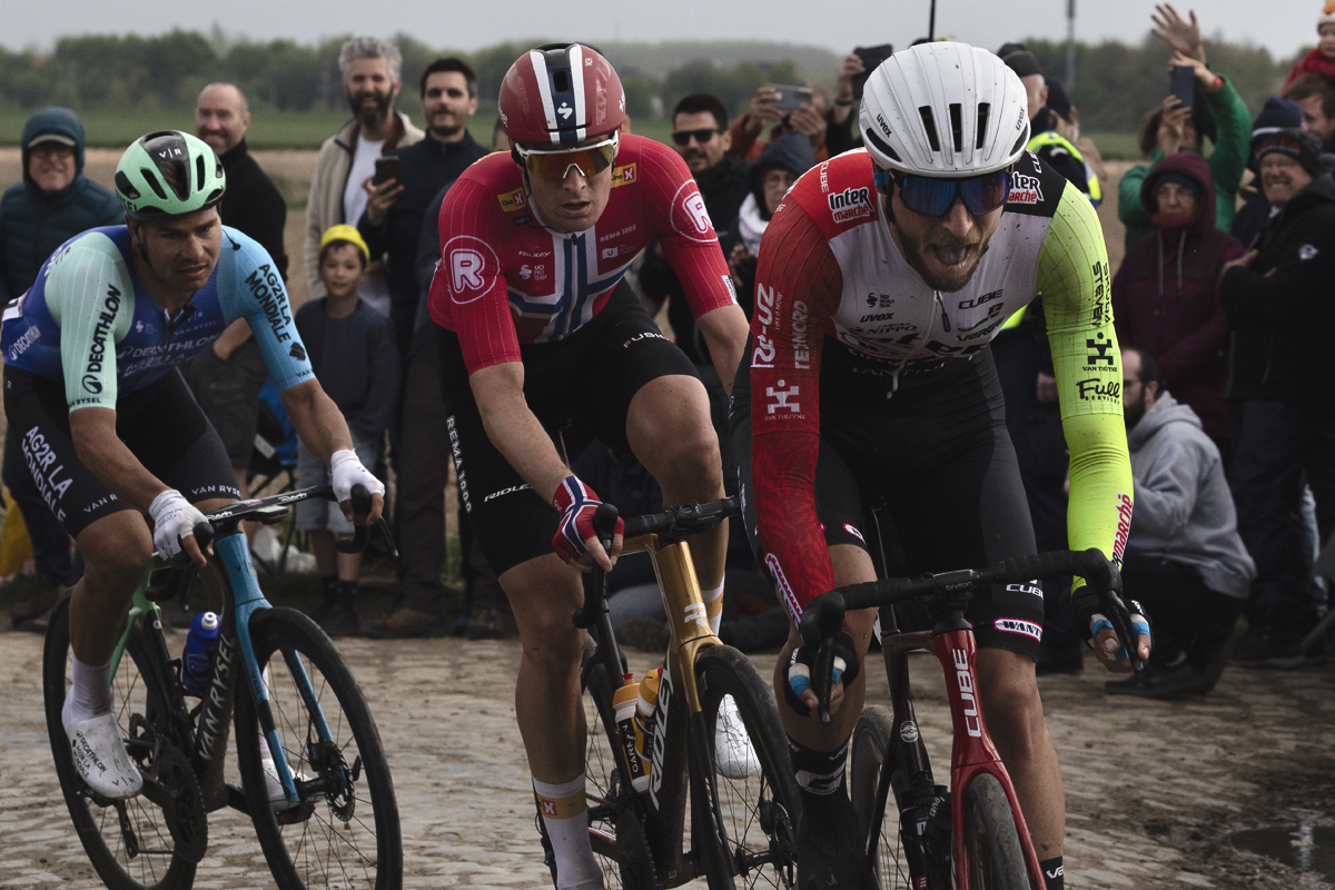 Paris Roubaix 2025 - A group of riders are watched on by fans during the race