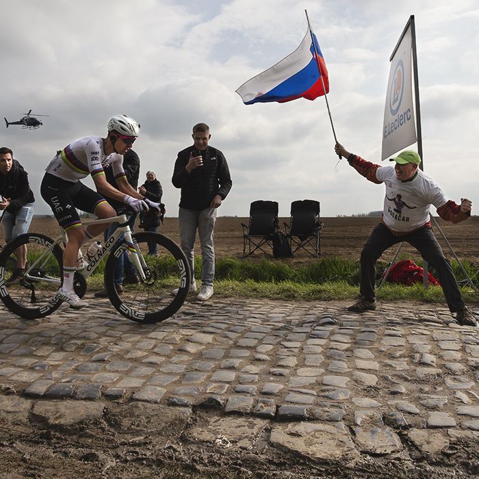 Paris Roubaix 2025 - Tadej Pogačar is enocouraged by an enthusiastic flag waving fan during the race on the Carrefour De L’Arbre sector