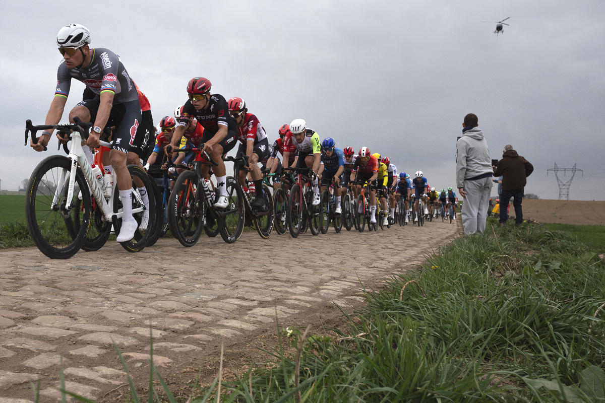 Paris Roubaix 2025 - The peloton led by Mathieu van der Poel ride down the cobbled sector of Quérénaing à Maing