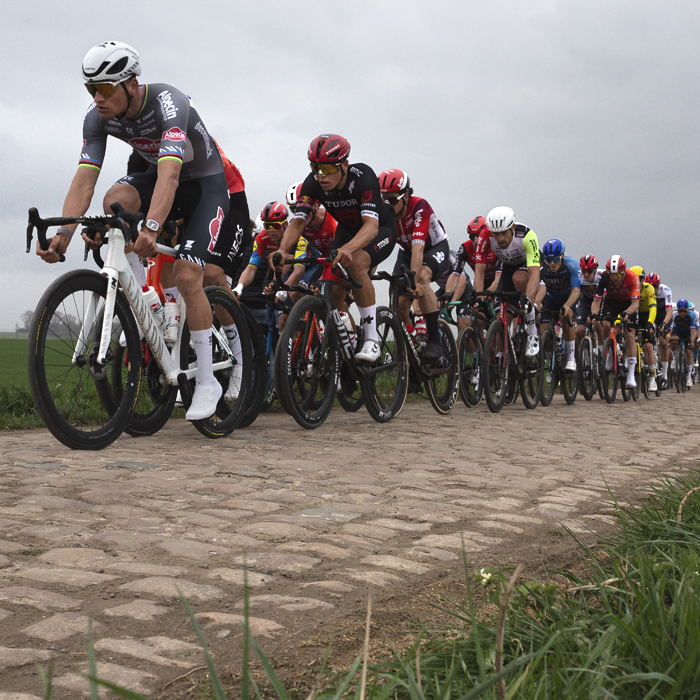 Paris Roubaix 2025 - The peloton led by Mathieu van der Poel ride down the cobbled sector of Quérénaing à Maing