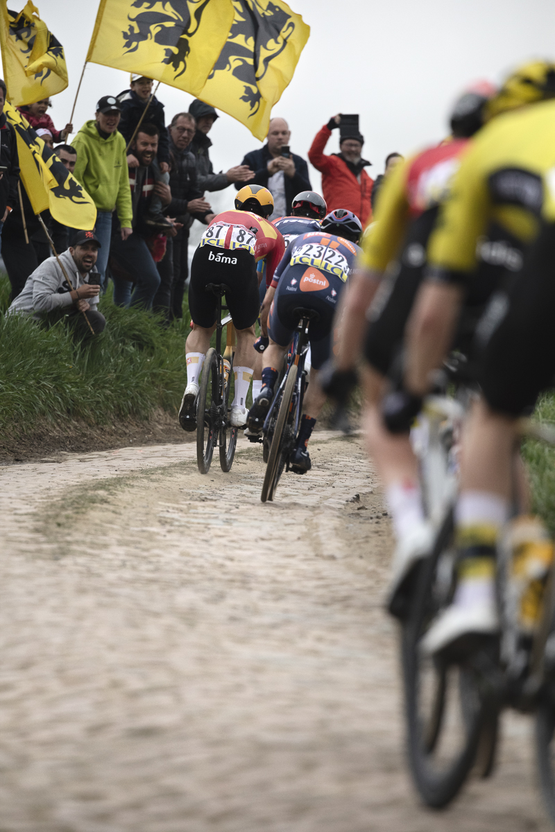 Paris Roubaix 2025 - Riders on Quérénaing à Maing with fans flying the flag of Flanders
