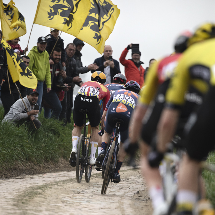 Paris Roubaix 2025 - Riders on Quérénaing à Maing with fans flying the flag of Flanders