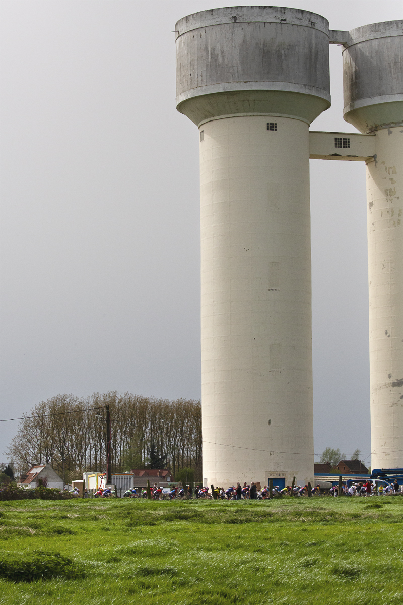 Paris Roubaix Femmes 2024 - The riders are drawfed by the water tower on the Hornaing à Wandignies sector