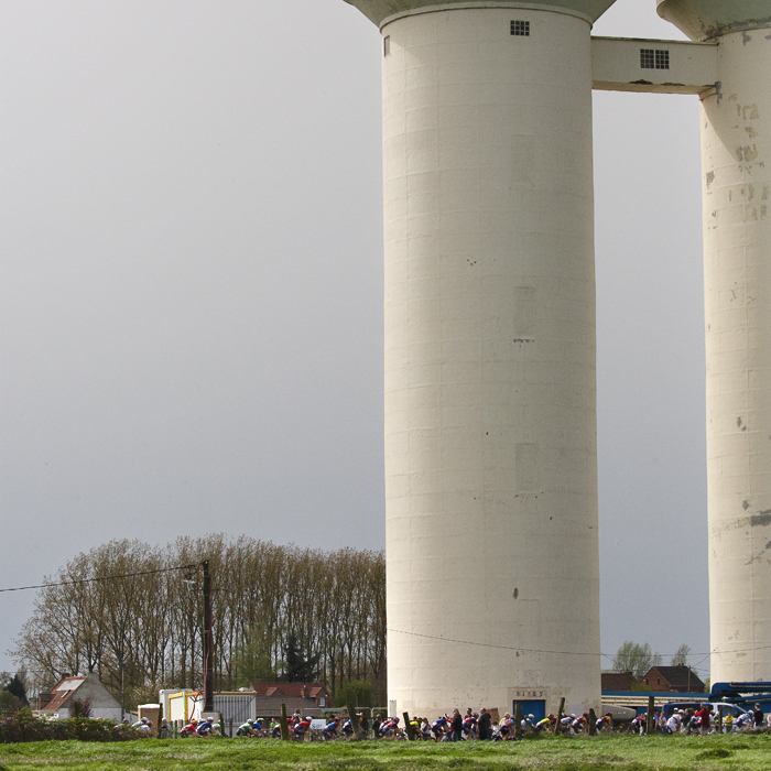 Paris Roubaix Femmes 2024 - The riders are drawfed by the water tower on the Hornaing à Wandignies sector