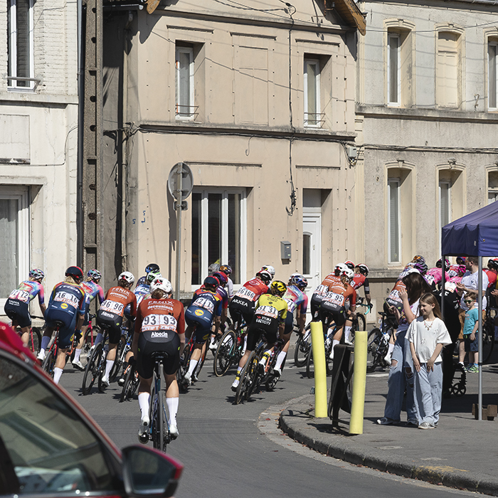 Paris Roubaix Femmes 2025 - Riders round a corner watched by young spectators at the start of the race