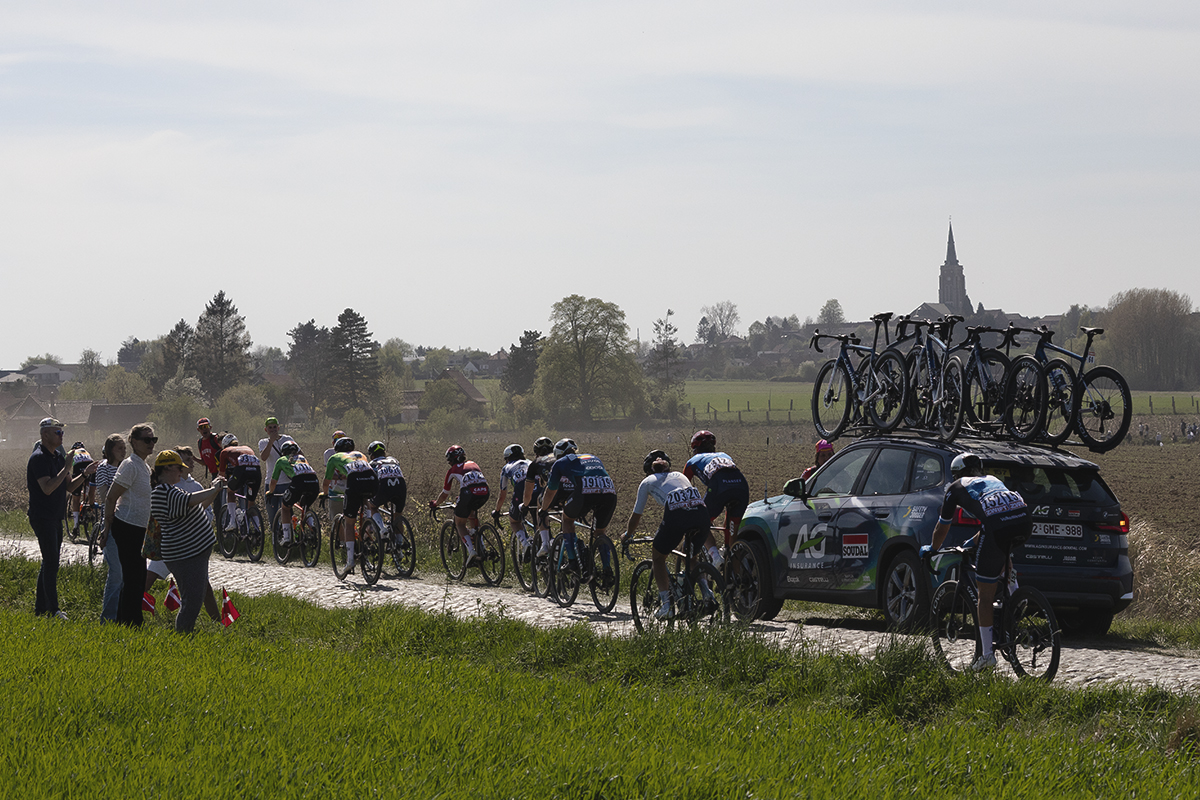 Paris Roubaix Femmes 2025 - Danish fans watch a group of riders pass with a church seen in the distance