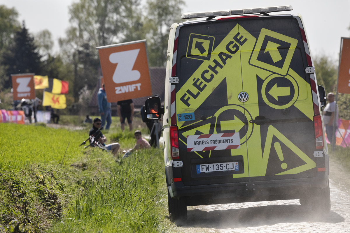 Paris Roubaix Femmes 2025 - A race organiser’s van with Fléchage written on the back on the cobbles