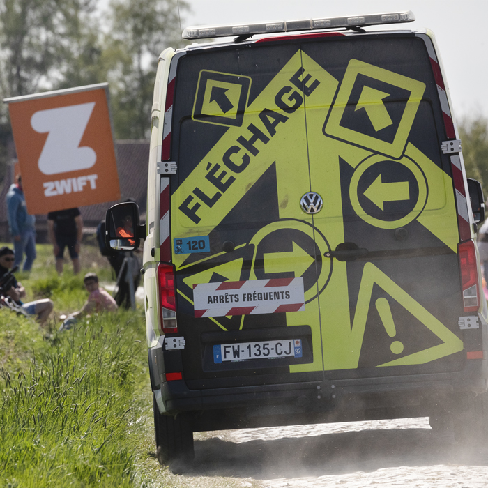 Paris Roubaix Femmes 2025 - A race organiser’s van with Fléchage written on the back on the cobbles