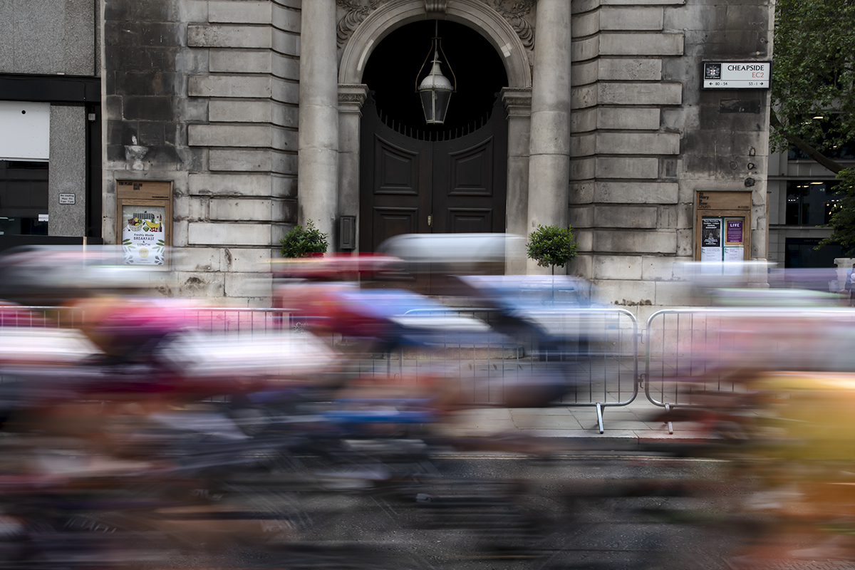 RideLondon Classique 2024 - The peloton speeds past the ornate doorway of St Mary-le-Bow Church on Cheapside in London