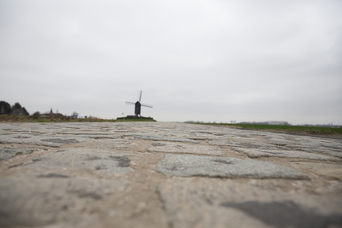 Ronde van Vlaanderen 2023 - Close up of the cobbles of Huisepontweg with the Schietsjampettermolen windmill in the distance