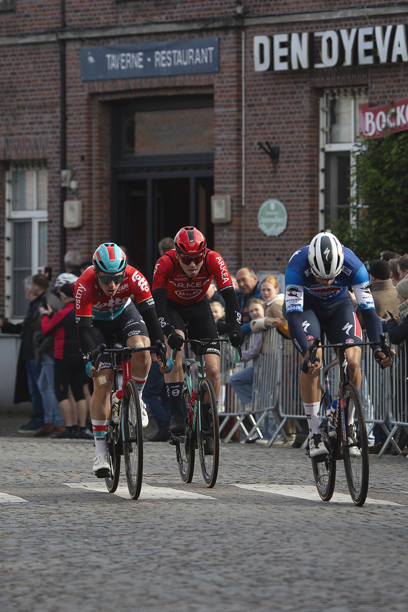 Ronde van Vlaanderen 2024 - Riders race past a cafe in Bazel
