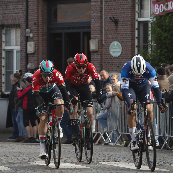 Ronde van Vlaanderen 2024 - Riders race past a cafe in Bazel