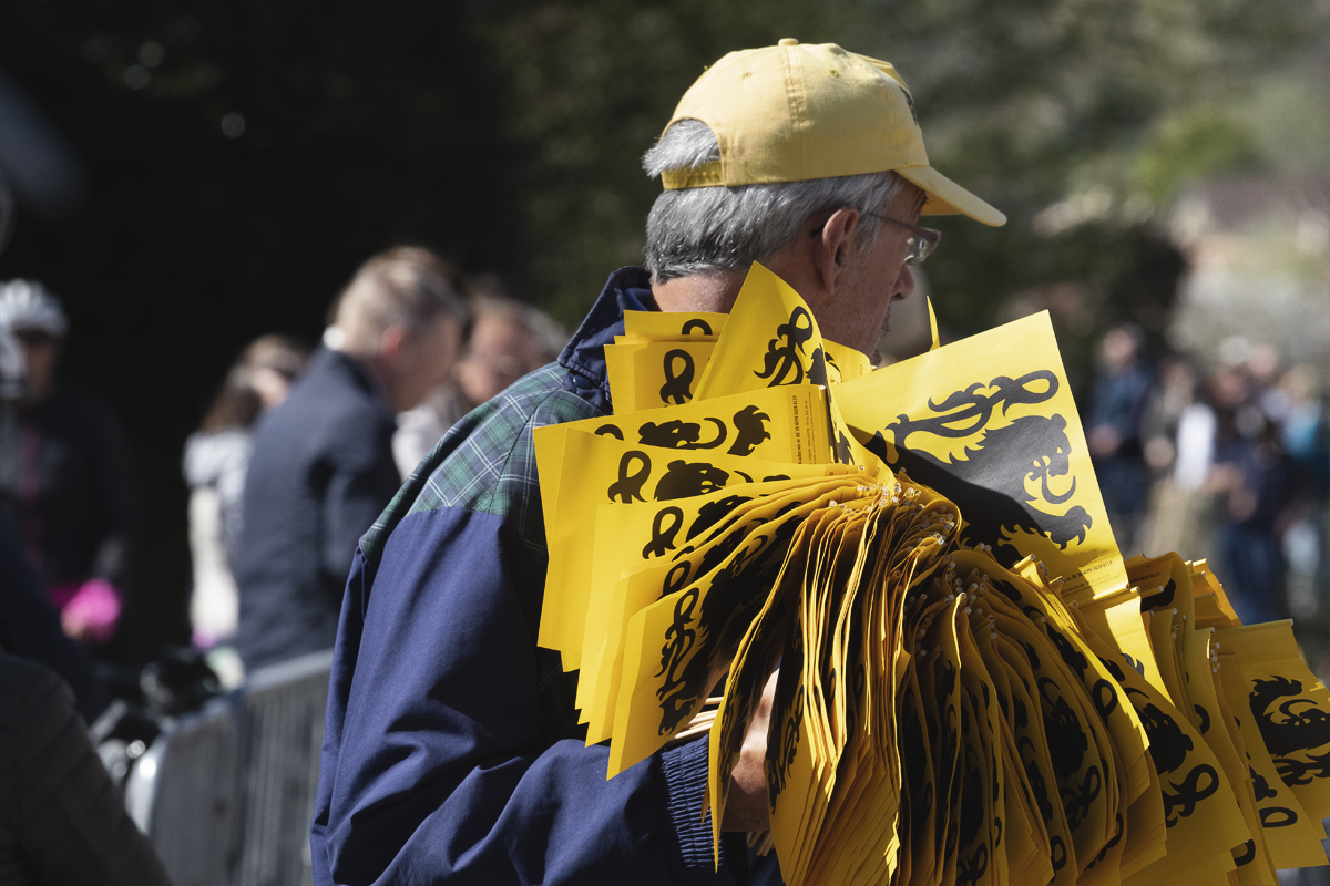 Ronde van Vlaanderen 2025 - A man, his arms laden with flags of Flanders to give out to the crowds